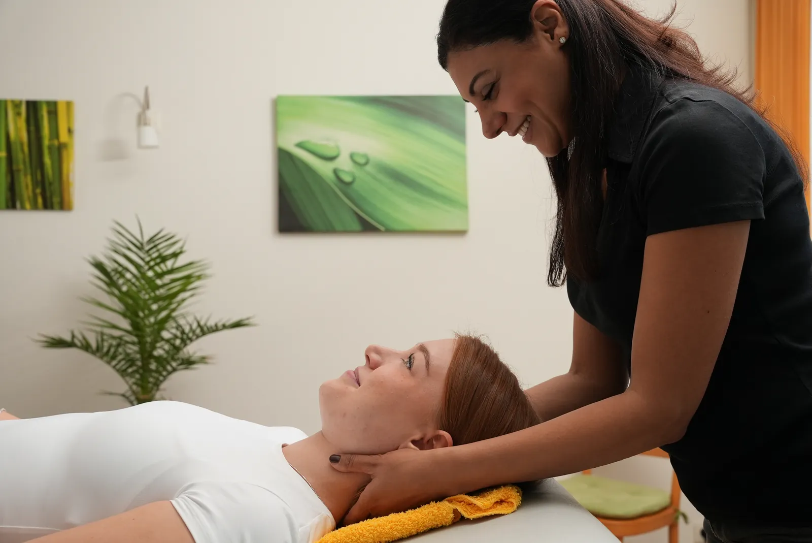 Physiotherapeutin behandelt Kiefer und Nacken einer liegenden Patientin